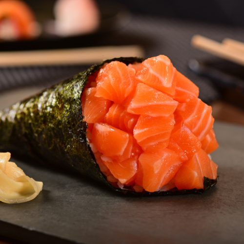 Temaki sushi made with fresh raw salmon cubes on rustic backgroundTemaki sushi made with fresh raw salmon cubes on rustic background